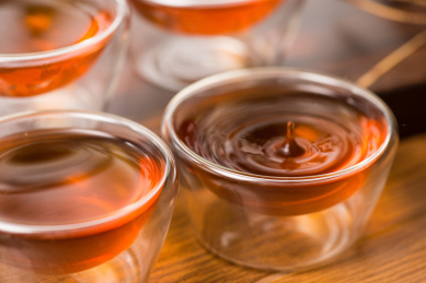 四个透明玻璃茶杯,杯子里有红茶,一滴茶倒入杯中有水珠