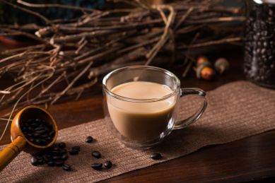 透明玻璃咖啡杯中的咖啡在原木色桌面上