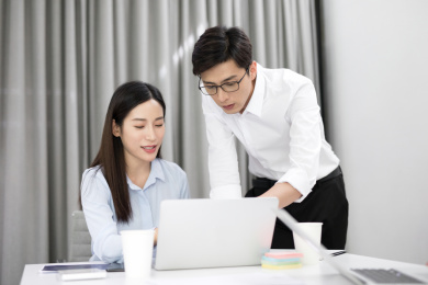 两位年轻的同事在办公室内讨论相关的工作问题