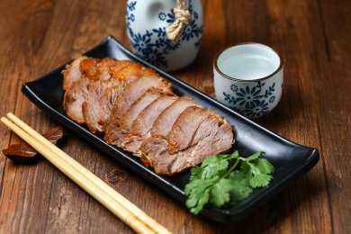 黑色盘子里的酱牛肉和白酒酒壶酒杯酒具放在木桌上