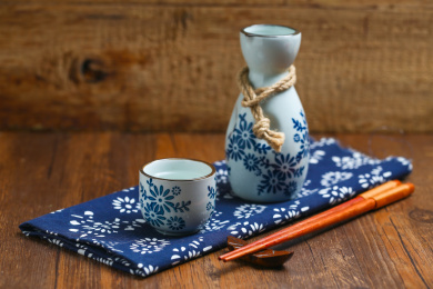日本清酒白酒酒壶酒杯酒具和筷子放在蓝花布上