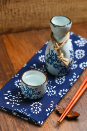 日本清酒白酒酒壶酒杯酒具和筷子放在蓝花布上