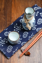 日本清酒白酒酒壶酒杯酒具和筷子放在蓝花布上俯拍