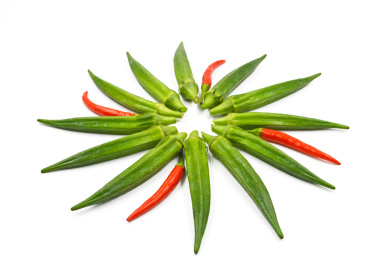 放射状的摆在白色背景上的绿色蔬菜秋葵及红色小辣椒