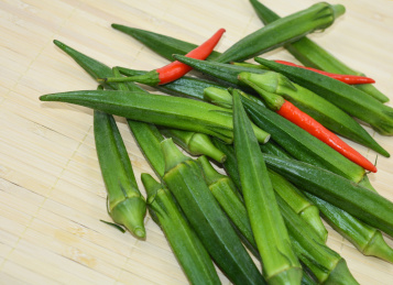 放在竹盖帘上的绿色蔬菜秋葵及红色的朝天椒