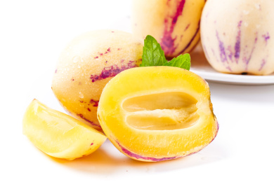 白底上装在白盘里的人参果前放一个完整的人参果和半个切开的人参果和一个人参果果瓣