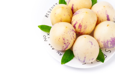 白底上装在白盘里的用绿叶修饰的一盘人参果