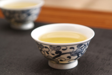 青花瓷茶杯和绿茶在黑色木桌上的特写镜头