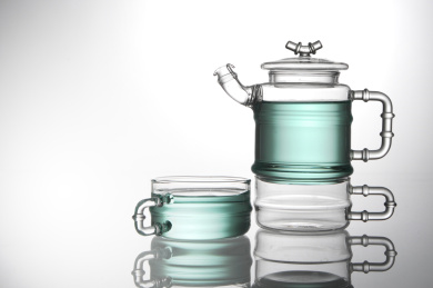 透明玻璃复古茶壶茶杯中的湖蓝色饮料，在白色背景中的静物摄影，