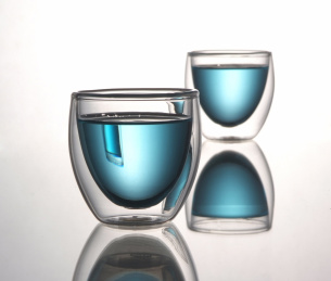 两个圆弧形透明玻璃水杯中的蓝色液体在白色背景中，抽象图案