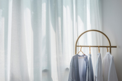 白色纱帘前衣架上悬挂的衣服