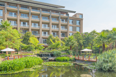 蓝天白云下中式设计酒店建筑外立面,人工湖倒