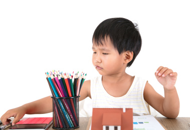 中国小女孩在玩耍桌子上的各种物品：小房子模型，笔筒，计算器和文件资料