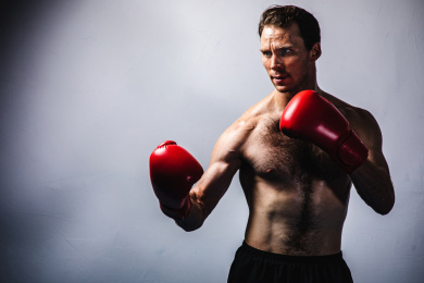 背景分离特写上半身裸露的英俊男性戴着拳套在挥拳