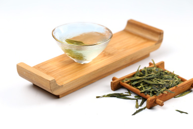 玻璃茶杯斗笠杯里的西湖龙井茶和茶叶放在白色背景上