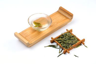 玻璃茶杯斗笠杯里的西湖龙井茶和茶叶放在白色背景上