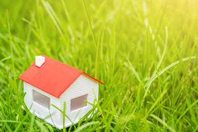 房子模型放在阳光下的草坪上——买房概念图片