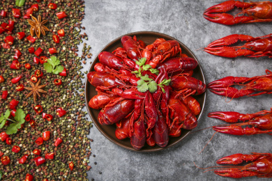 灰黑底上一半调料一半小龙虾中间放着一盘小龙虾