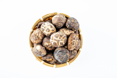 白背景上竹筛子装满晒干的真菌食材香菇