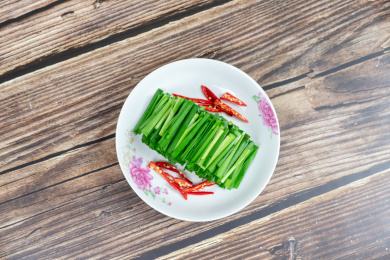 木纹桌子上白色盘子里的绿色韭菜食材