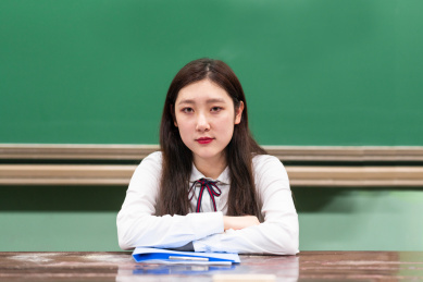 校园教室内,黑板前,一个坐姿端正的女学生