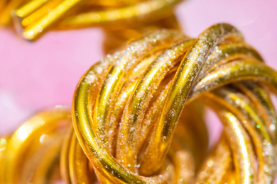 在粉色背景上的弯曲缠绕的金色铝丝