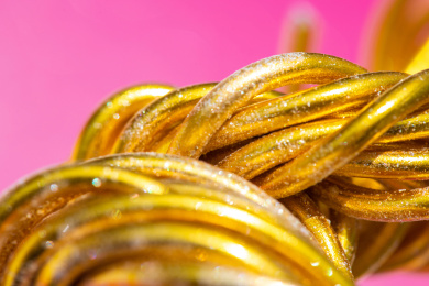 在粉色背景上的弯曲缠绕的金色铝丝