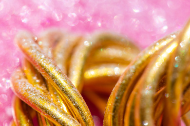 在粉色背景上的弯曲缠绕的金色铝丝