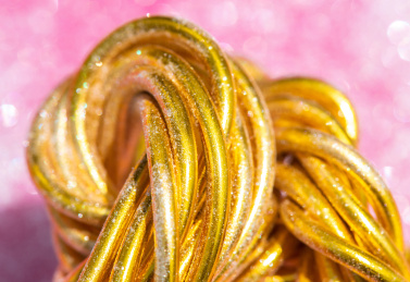 在粉色背景上的弯曲缠绕的金色铝丝