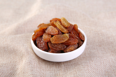 一堆红色的中国红香妃葡萄干放在复古的麻布上