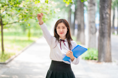 校园内美丽的女学生拿着文件夹为大家加油