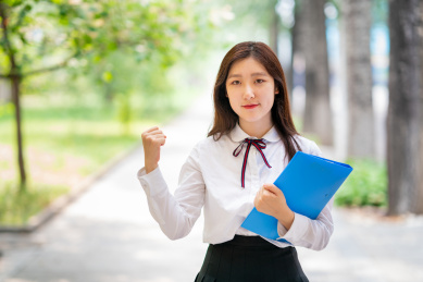 校园内美丽的女学生拿着文件夹为大家加油