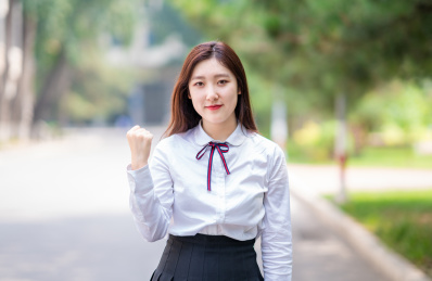 校园内竖着拳头为考试学生加油的美丽中国女学生