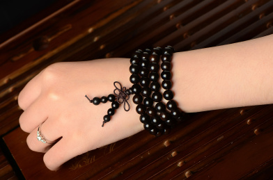 复古风格背景上的黑檀木佛珠手串佩戴图