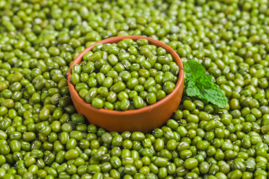 绿豆背景上装着绿豆的木碗