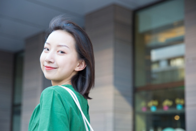 在室外一名年轻的亚裔女职员回头微笑