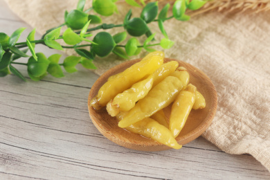 一碟黄色泡椒放在木纹桌面上