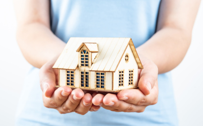 女性双手捧起一栋小房子小木屋