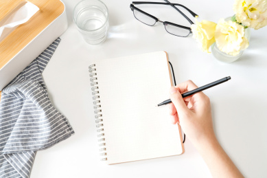 在摆放着眼镜、水杯等物品的桌面上 书写的场景