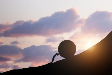 一个人推着巨大的岩石向着山峰的山顶前进,克服着巨大的困难,坚持走向成功