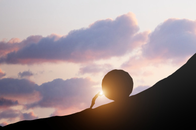 一个人推着巨大的岩石向着山峰的山顶前进,克服着巨大的困难,坚持走向成功