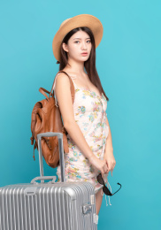  蓝色背景里，手里拿着墨镜准备出发的美丽东方女孩