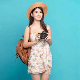 蓝色背景里，手上拿着单反相机的美丽亚洲女孩
