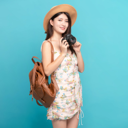 蓝色背景里，手上拿着单反相机的美丽亚洲女孩