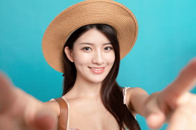 蓝色背景里，对着镜头正在自拍的东方美女