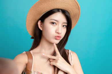 蓝色背景里，对着镜头正在自拍的东方美女