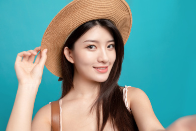 蓝色背景里，对着镜头正在自拍的东方美女