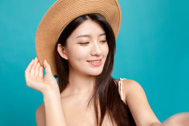 蓝色背景里，对着镜头正在自拍的东方美女