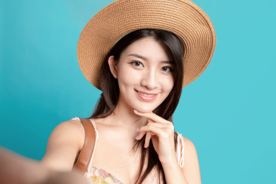 蓝色背景里，对着镜头正在自拍的东方美女