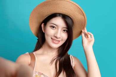 蓝色背景里，对着镜头正在自拍的东方美女